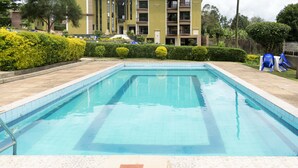 Una piscina rectangular con agua azul cristalina, rodeada de baldosas de piedra.