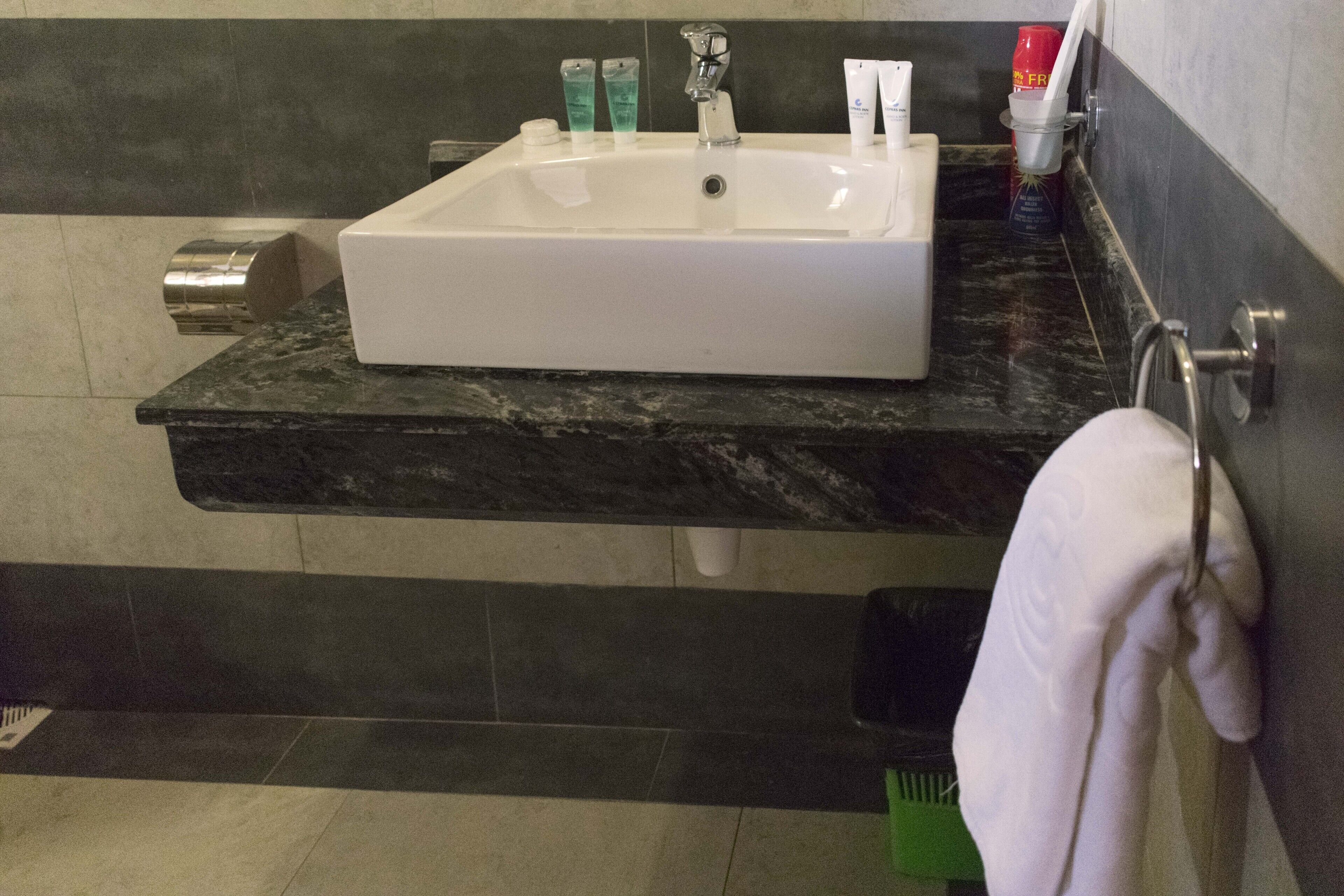 A bathroom with a white sink, dark marble countertop, and a towel rack.