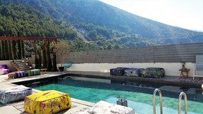 Una piscina al aire libre, sombrillas, sillones reclinables de piscina