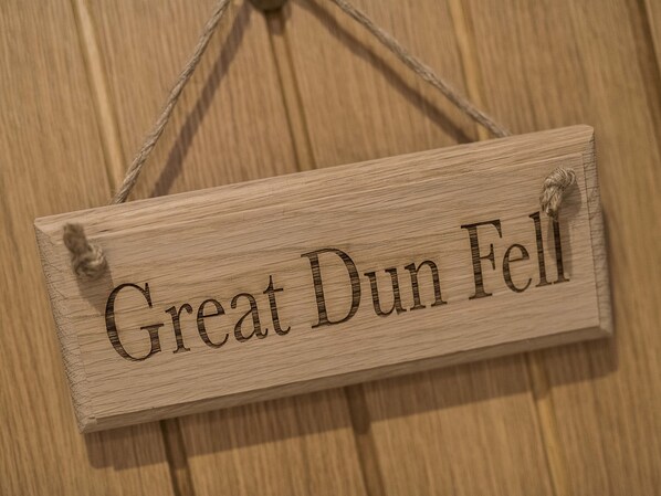 A wooden sign with the text "Great Dun Fell" hanging on a wooden wall.