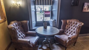 A corner seating area with two brown leather chairs and a round wooden table.