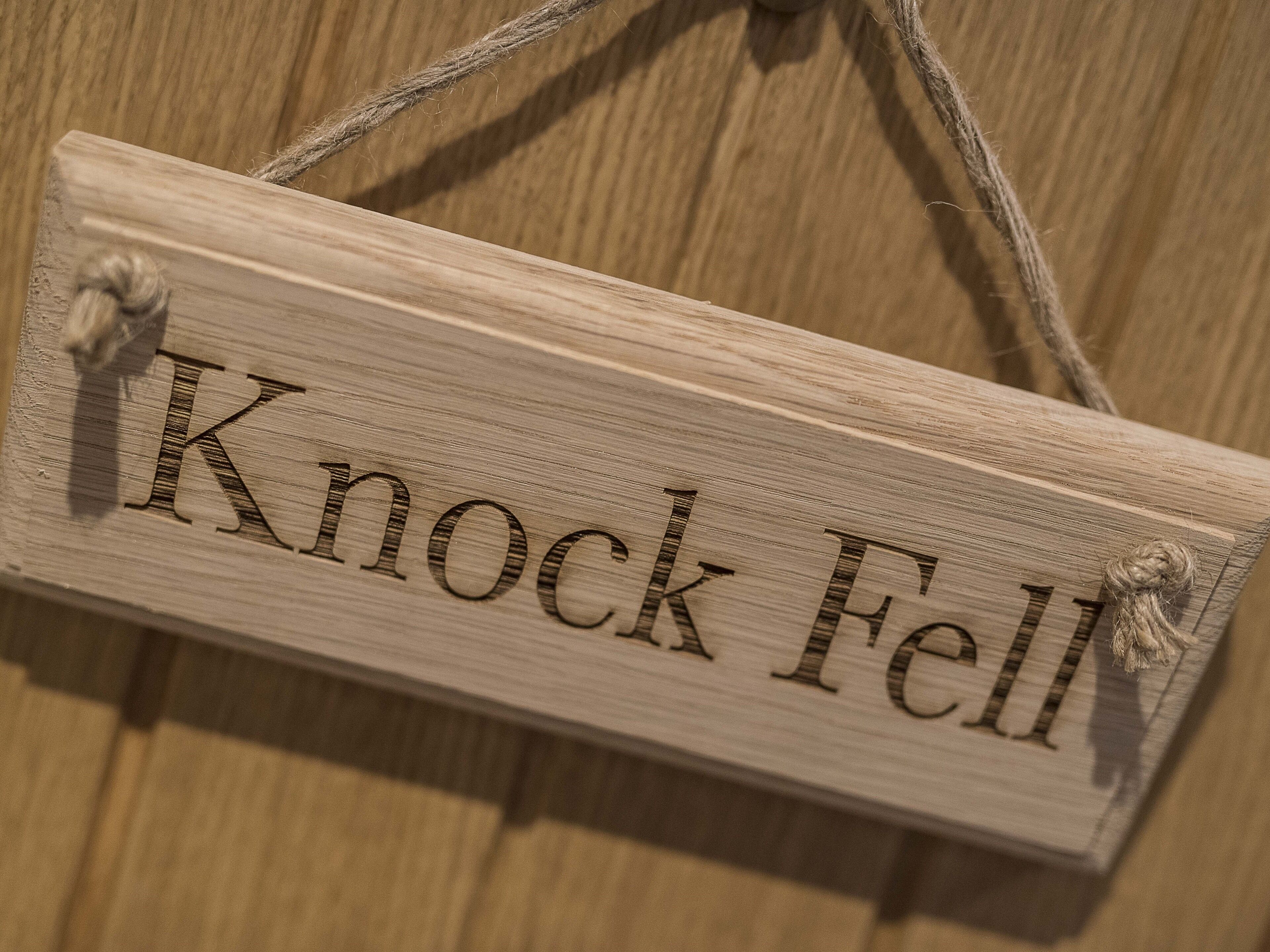 A wooden sign with the text "Knock Fell" and a rope handle.
