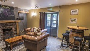 A cozy lounge area with a leather sofa, a wooden bench, and a bar area with stools.