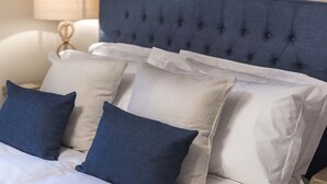 A neatly made bed with a tufted headboard, multiple pillows, and a bedside lamp.