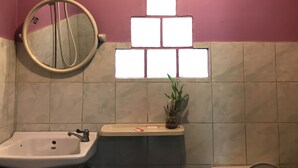Une salle de bain équipée d’un lavabo, d’un miroir et d’une fenêtre agrémentée d’un luminaire au design géométrique.