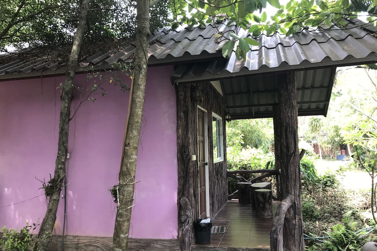Una estructura de madera cubierta con exterior morado, rodeada de árboles y vegetación.