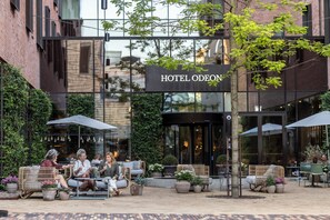 An outdoor seating area with wicker furniture and potted plants at Hotel Odeon.