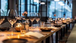 A restaurant table set with wine glasses, candles, and a flower centerpiece.
