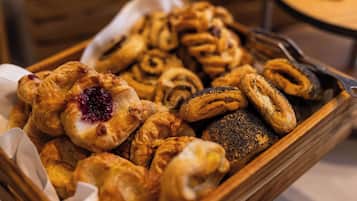 Una bandeja de madera con varios pasteles, incluyendo croissants y hojaldres rellenos.