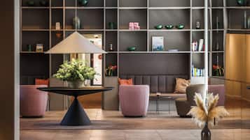 Eine moderne Lobby mit einem zentralen Tisch, einer Sitzecke und einem Bücherregal.