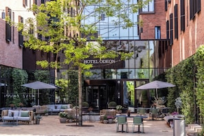 Un hotel con terraza al aire libre, un árbol y fachada de ladrillo.