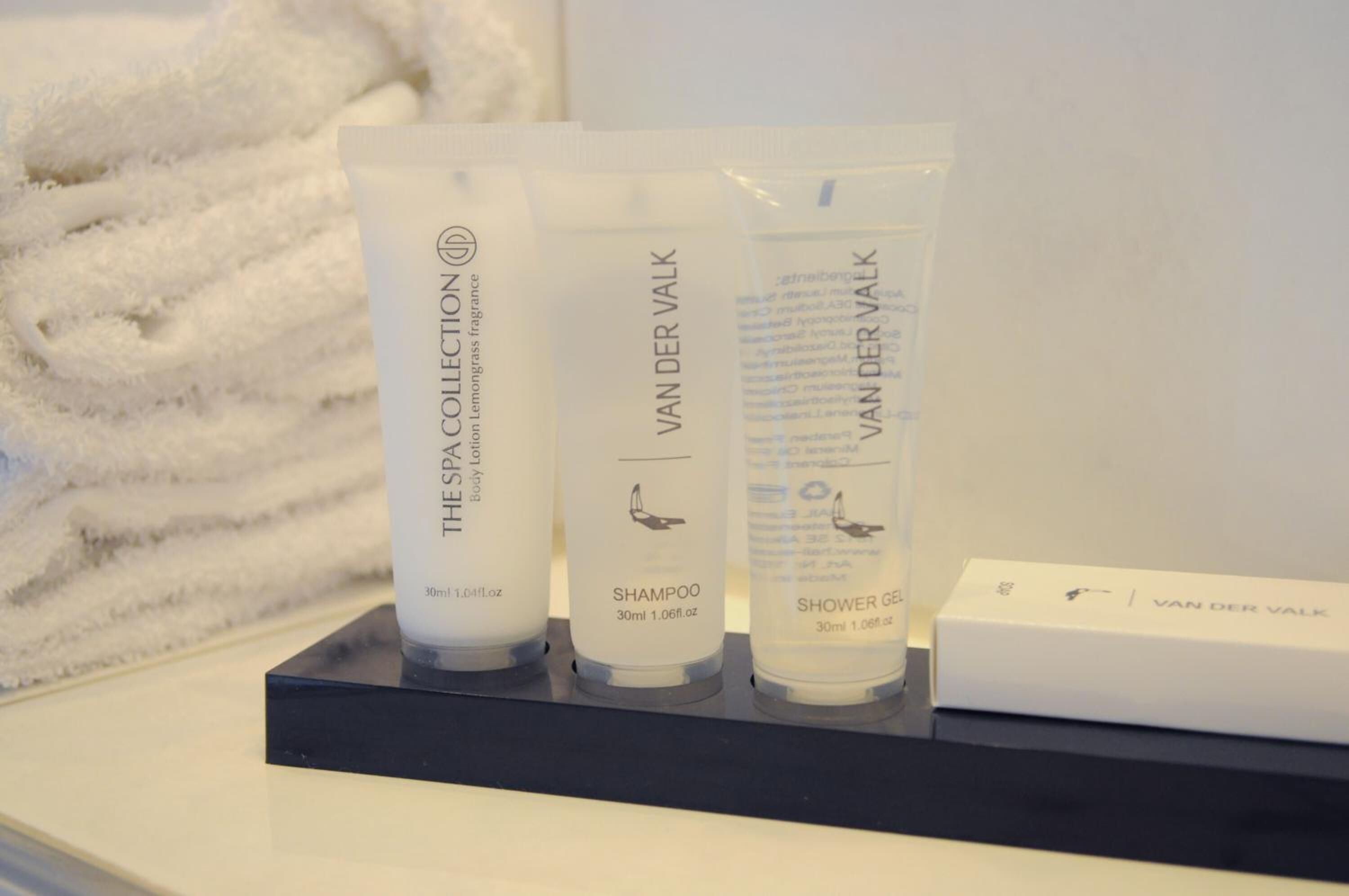 Trois bouteilles de lotion pour le corps Van der Valk et un paquet de gel douche sont exposés sur un présentoir.