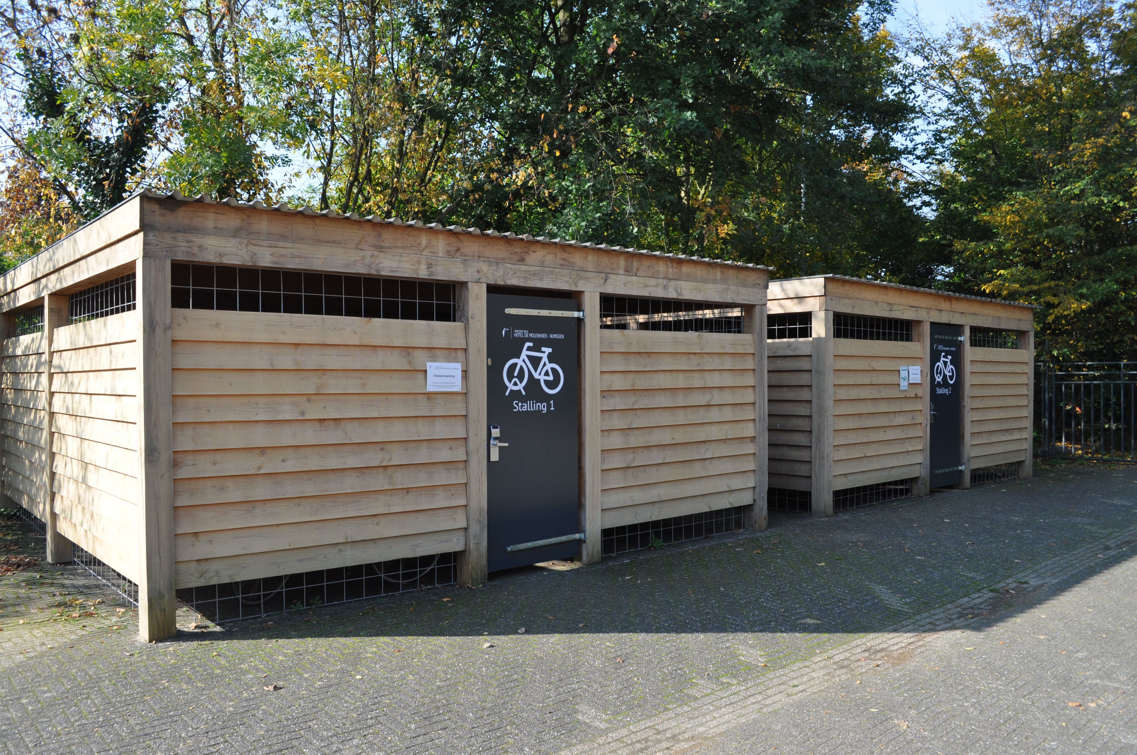 Een rij houten kraampjes met fietssymbolen, wat een fietsenparkeerplaats aangeeft.