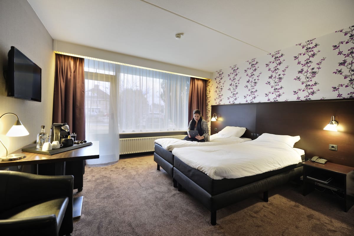 Une chambre d’hôtel comprenant un lit, des tables de chevet, un bureau avec une lampe, une chaise et un téléviseur.