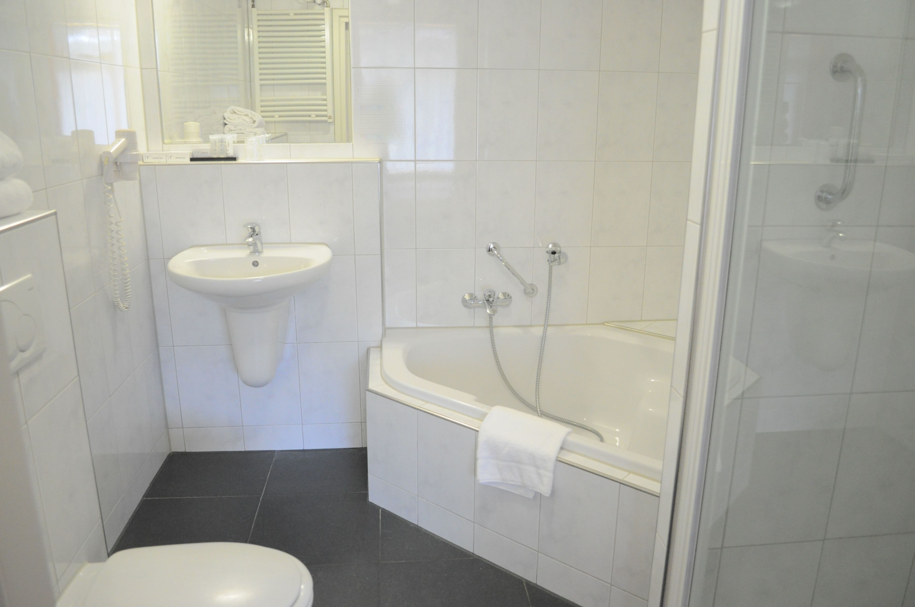 Ein Badezimmer mit Toilette, Waschbecken, Badewanne und Dusche.
