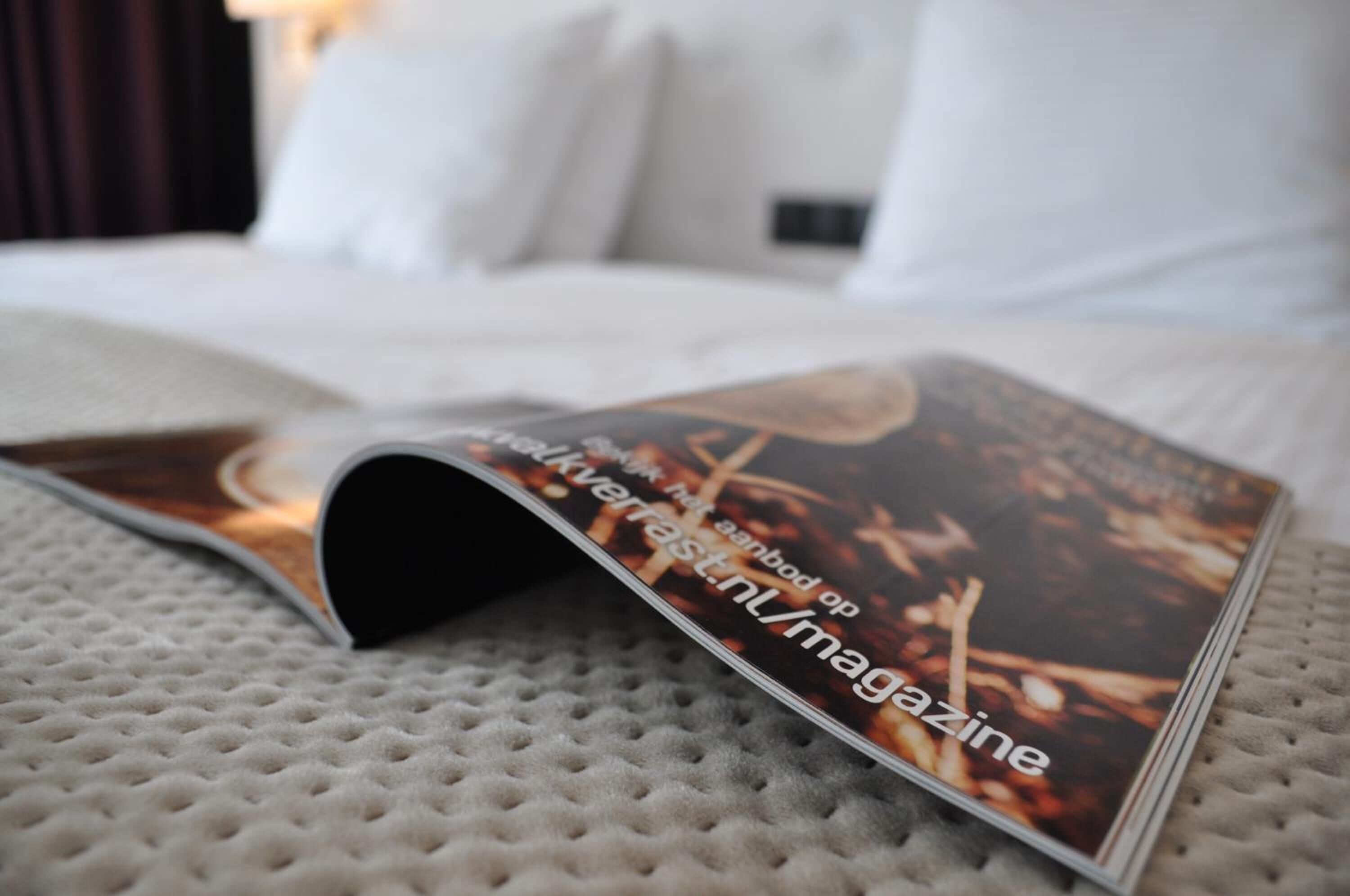 Eine Zeitschrift liegt auf einem Bett, deren Einband eine strukturierte Oberfläche hat.