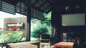A modern building with a large sign in a foreign language, wooden furniture, and a view of greenery outside. - Kannawat Resort (Ban Na)