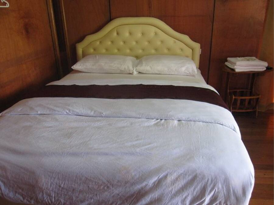 A bed with a tufted headboard, white bedding, and a brown throw blanket.