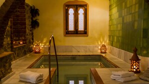A spa area with a hot tub, stone walls, and decorative lighting. - La Molinilla Apartamentos Y Hammam - Adults Only (Linares de la Sierra)