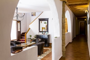 A hallway with a wooden staircase, a black cabinet, and a mirror on the wall. - La Molinilla Apartamentos Y Hammam - Adults Only (Linares de la Sierra)