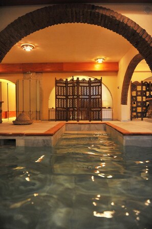 A pool area with a stone archway, a decorative wooden gate, and a tiled floor. - La Molinilla Apartamentos Y Hammam - Adults Only (Linares de la Sierra)