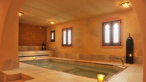 A spa room with a large pool, a bench, and a candle. - La Molinilla Apartamentos Y Hammam - Adults Only (Linares de la Sierra)