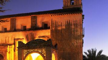 A historic building with a prominent bell tower and a courtyard featuring a stone fountain.