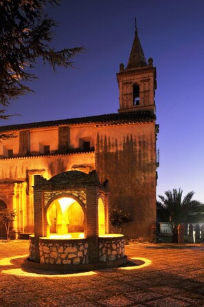 A historic building with a prominent bell tower and a courtyard featuring a stone fountain. - La Molinilla Apartamentos Y Hammam - Adults Only (Linares de la Sierra)