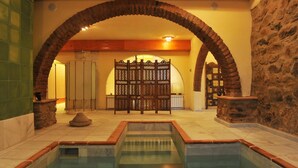 A pool area with a stone wall, a wooden fence, and a tiled floor. - La Molinilla Apartamentos Y Hammam - Adults Only (Linares de la Sierra)