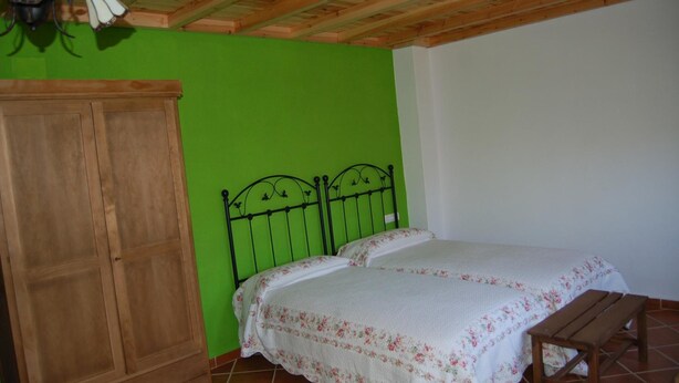 Ein Zimmer mit einem hölzernen Bett, einem Schrank aus Holz und einer grünen Wand.