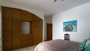 Une chambre à coucher avec un lit, une armoire en bois et un tableau représentant une tortue de mer accroché au mur.