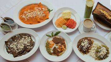 Una mesa con diversos platos, incluyendo enchiladas, un batido verde y un plato al horno.