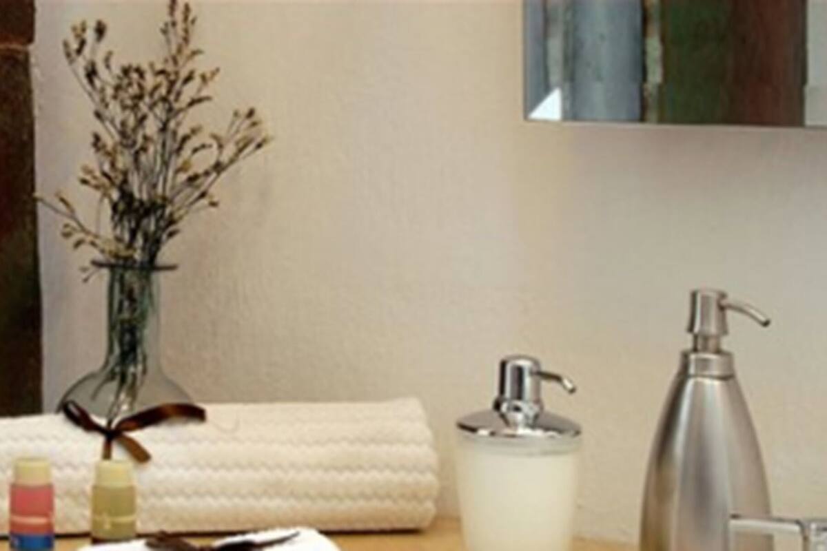 Een badkamer met een witte handdoek, een fles lotion, een zeepdispenser en een vaas met gedroogde bloemen.