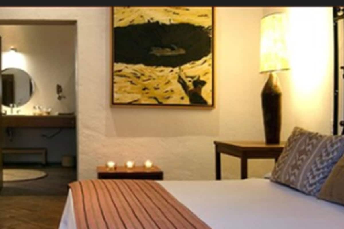 Hotelkamer met een bed, nachtkastje, lamp, schilderij aan de muur en uitzicht op de badkamer.