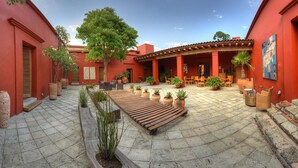 A courtyard with a wooden bench, potted plants, and outdoor seating.