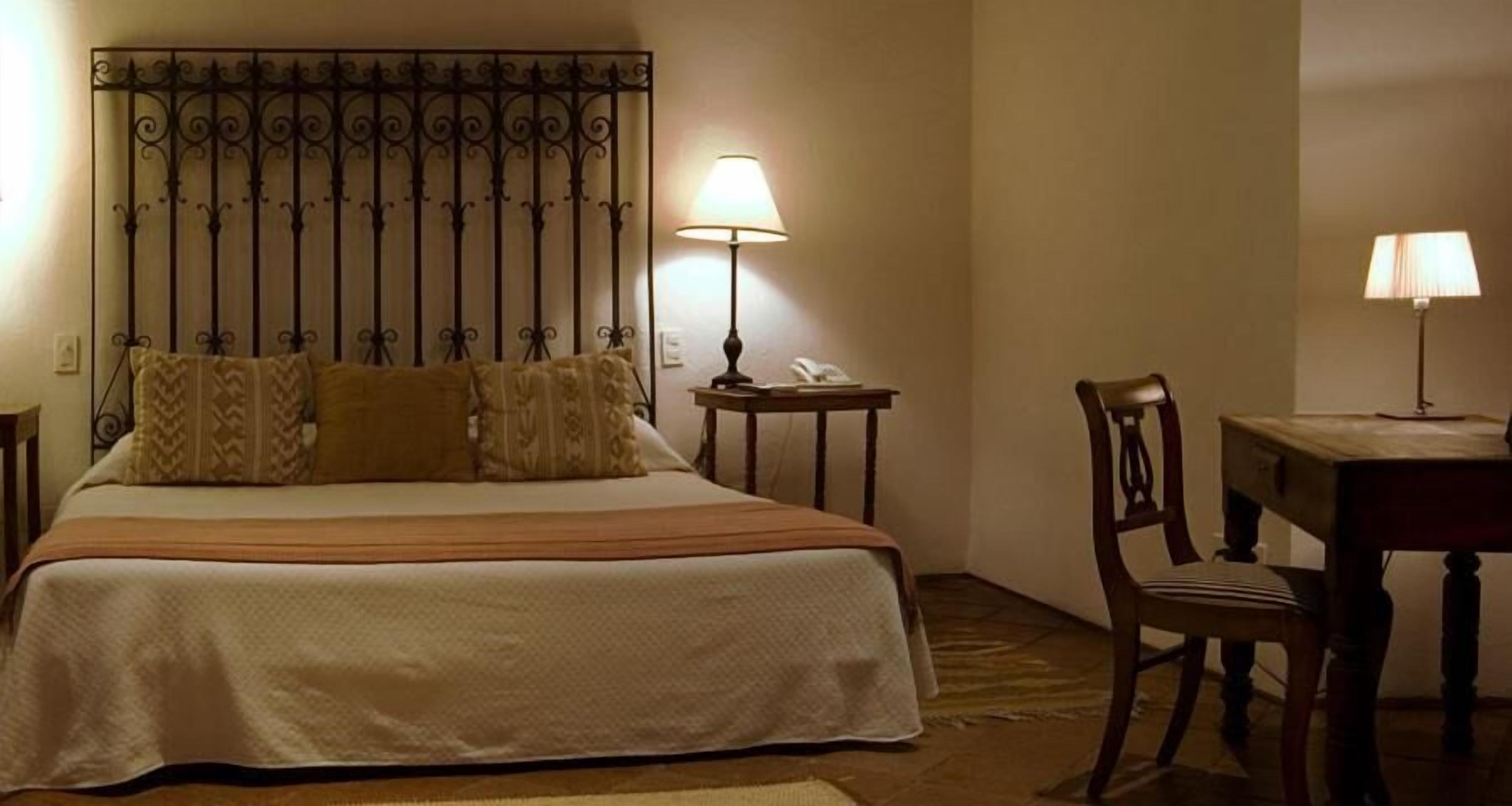 Ein Hotelzimmer mit Bett, Schreibtisch, Stuhl und Lampe.