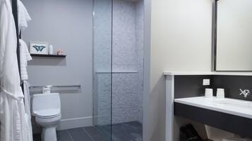 Une salle de bain moderne avec une douche à parois de verre, des toilettes blanches et un meuble-lavabo noir avec un miroir.