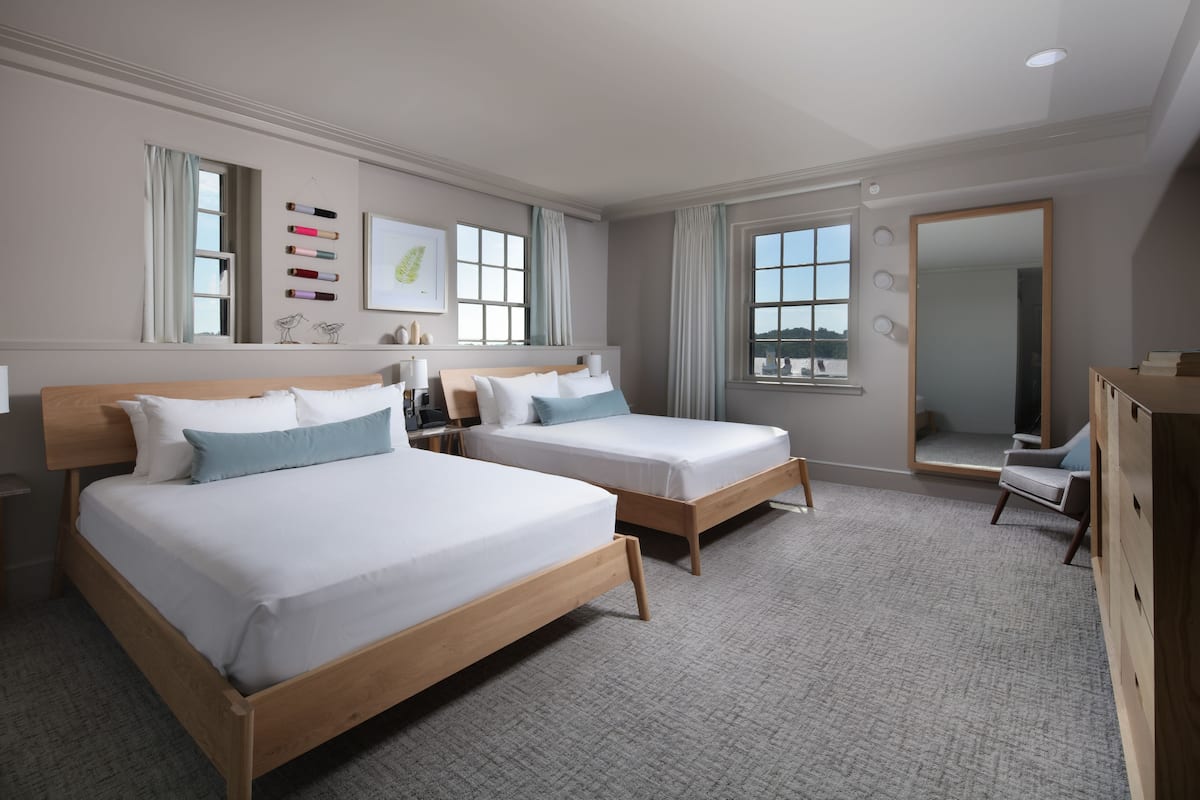 Une chambre d’hôtel avec deux lits, un grand miroir et une vue sur la ville.