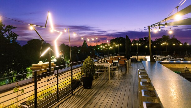 Een terras met buitenmeubels, lichtjes en een reling.