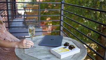 A person sitting at a round table with a laptop, a glass of champagne, and a book.