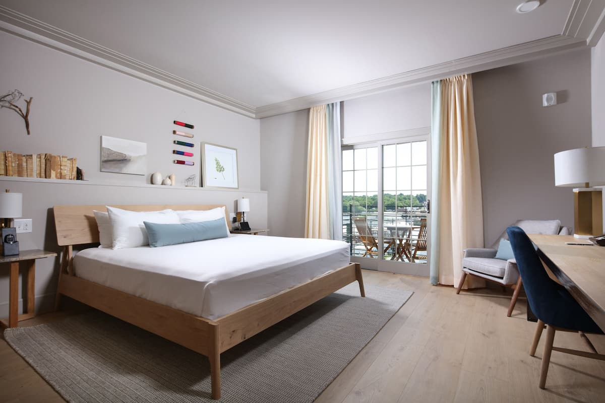Une chambre d’hôtel moderne avec un lit en bois, un bureau et un balcon offrant une vue agréable.