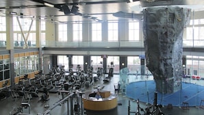 Een fitnessruimte met diverse trainingsapparaten, een grote klimmuur en een receptie.