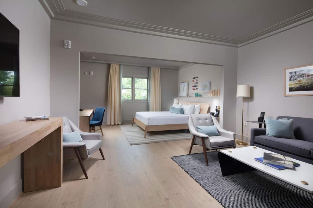 Une chambre d’hôtel moderne équipée d’un lit, de deux fauteuils, d’un bureau, d’un canapé et d’une table basse.