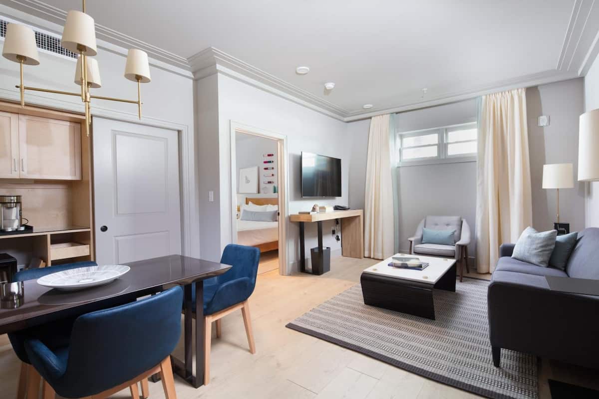 Une chambre d’hôtel moderne équipée d’un coin repas, d’un canapé, d’une télévision et d’un lit.