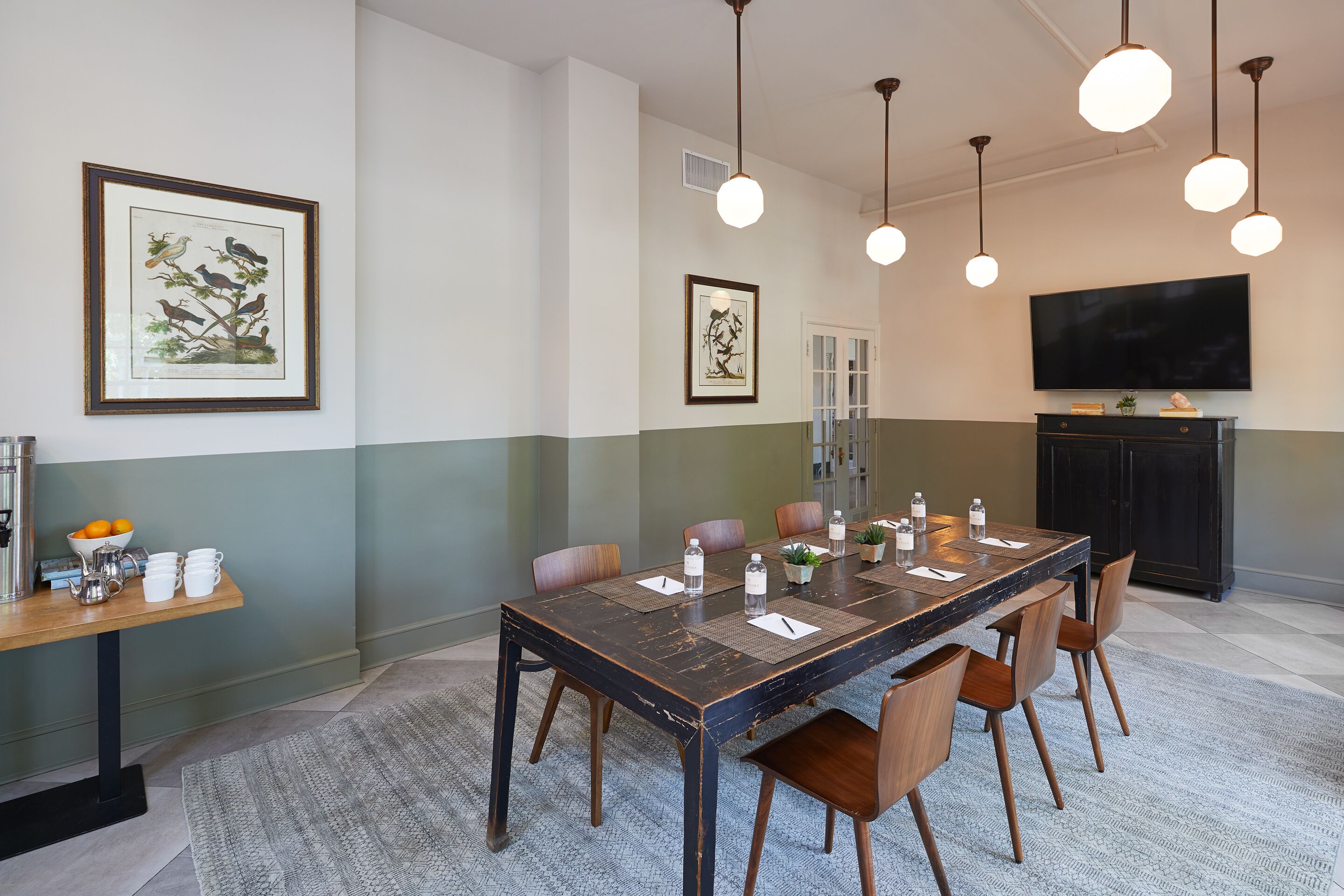 Un espace repas comprenant une longue table, des chaises et un téléviseur fixé au mur.