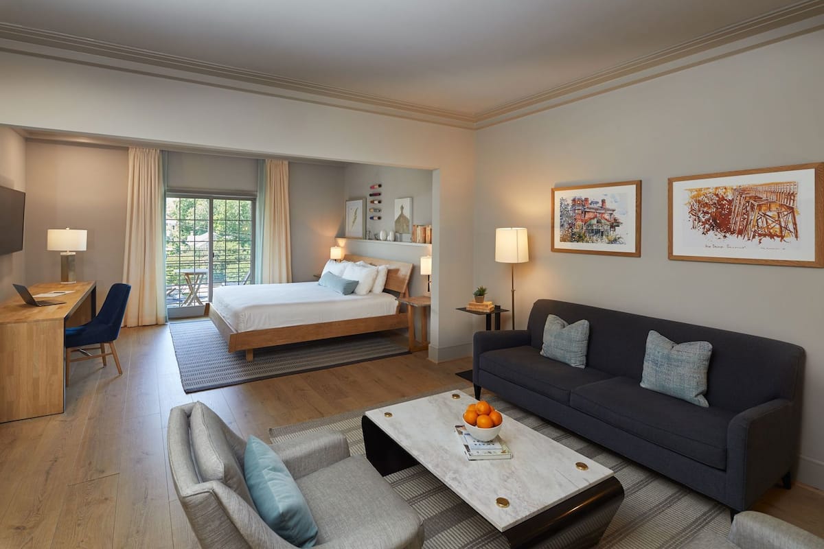 Une chambre d’hôtel avec un lit, un canapé, une table basse, un bureau et un téléviseur.