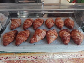 A display case with a variety of pastries, including croissants and other baked goods. - Donna sabella (Santa Flavia)