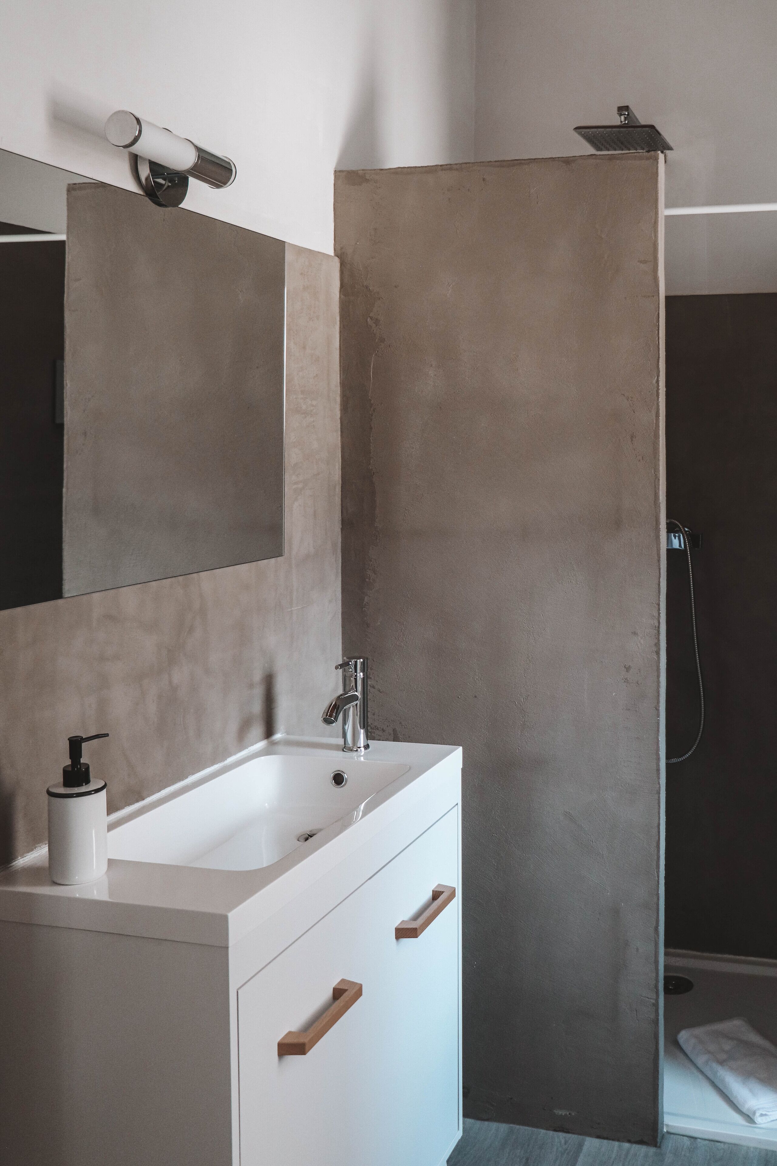 A bathroom with a white sink, a mirror, and a shower enclosure.