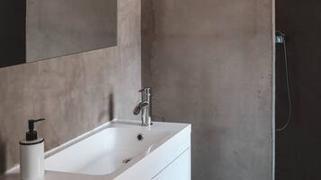 A bathroom with a white sink, a mirror, and a shower enclosure.