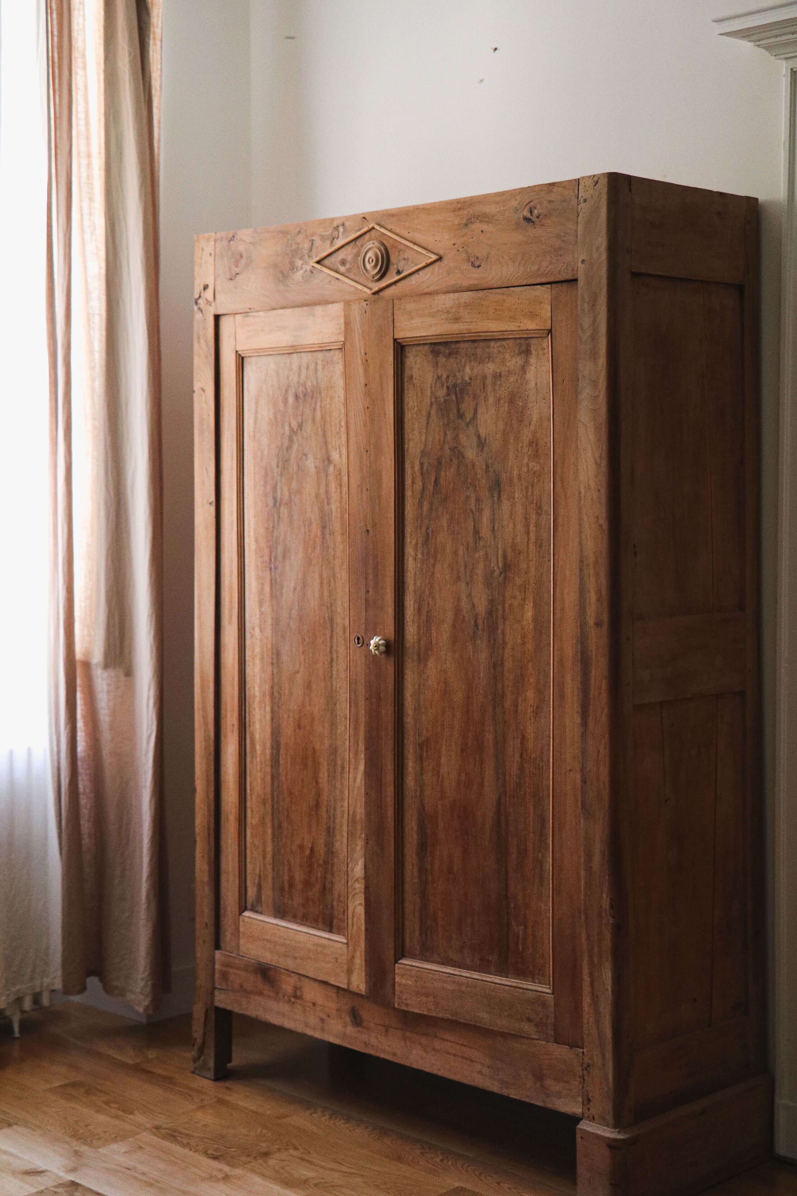 Ein schlichter, hölzerner Kleiderschrank mit einer Tür und einem kleinen Griff.